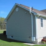 Side of a white/tan home with mitigation system