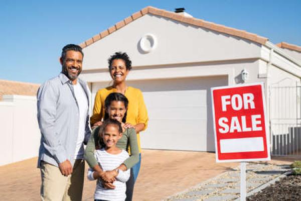 A family stands in front of a home they just purchased.